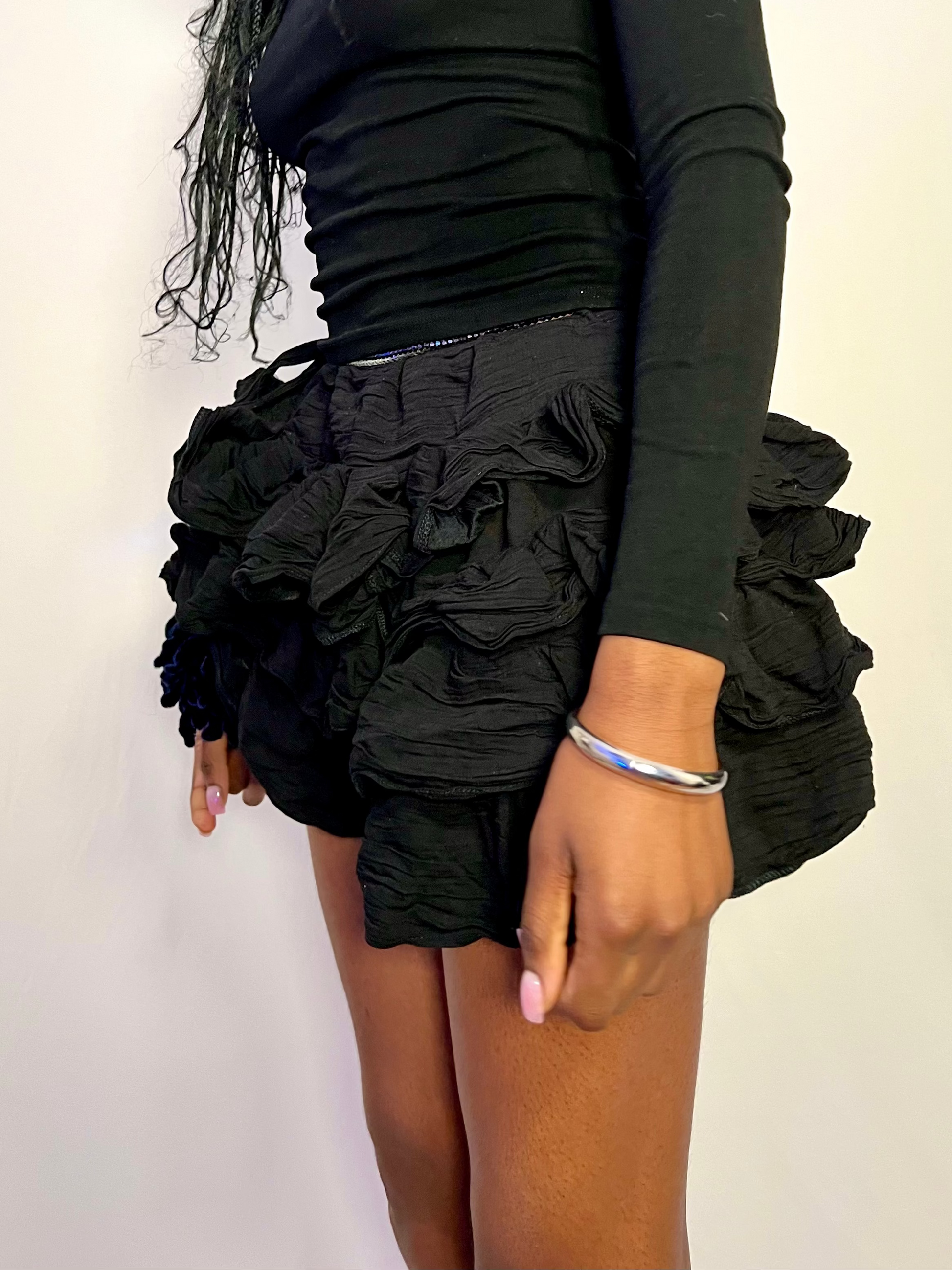 mini black ruffle skirt worn with a long sleeve basic black top